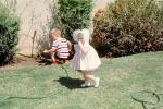 Girl with Bonnet, Backyard, Hose, Boy, Lawn, April 1965, 1960s, PHEV01P01_15