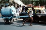 Man pulling on a cart, water, barrel, taxi cab, car, on the Streets of Mumbai, VCVV01P01_05.0569